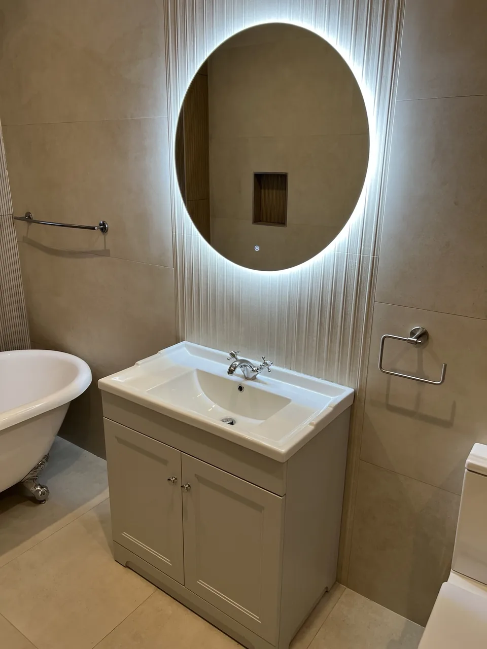 Closer view of the vanity cabinet, basin and oval illuminated mirror in the same Limerick bathroom