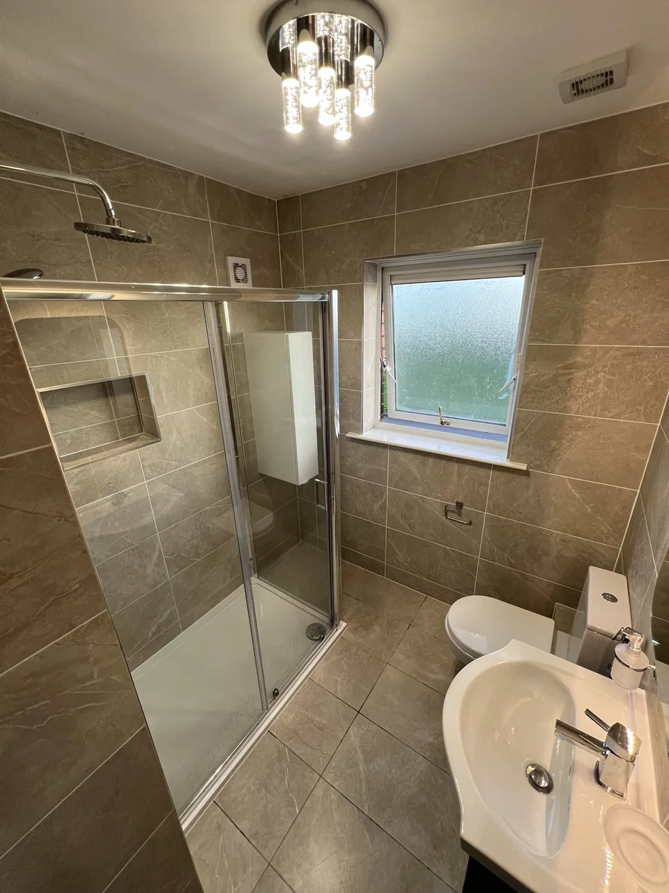 Completed Limerick bathroom with a glass shower enclosure, shower tray, recessed tiled shelf and coordinated wall and floor tiles